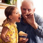 grandfather feeding his granddaughter sour cream
