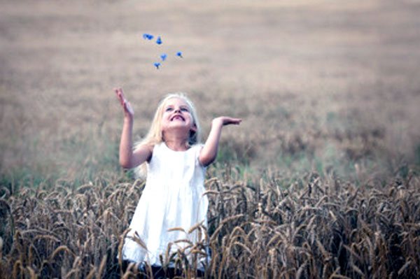 Девочка стоит посреди поля с колосьями
