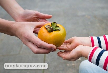 Мама дает ребенку оранжевый фрукт